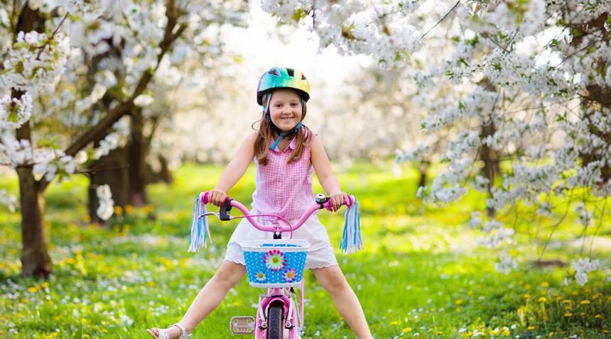 Happy girl on bike amongst cherry blossoms