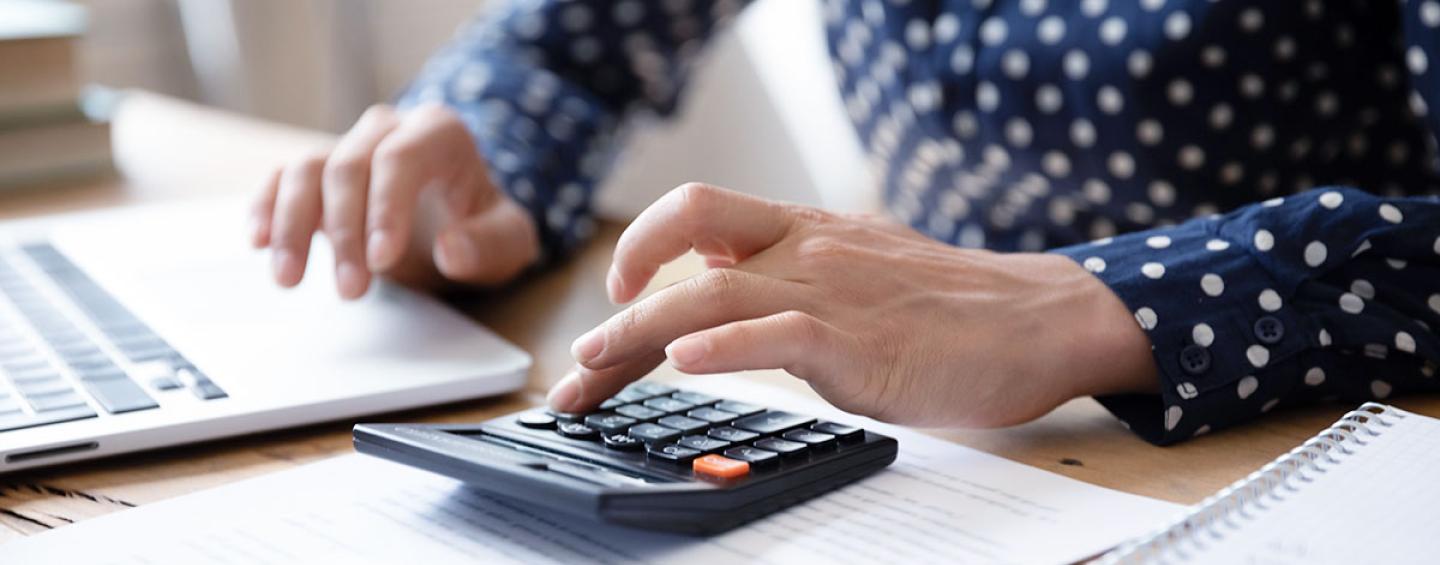 Woman with calculator and laptop.