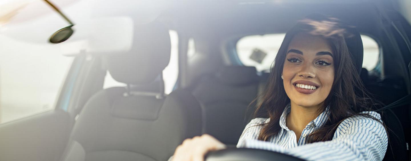 Woman smiling and driving a car