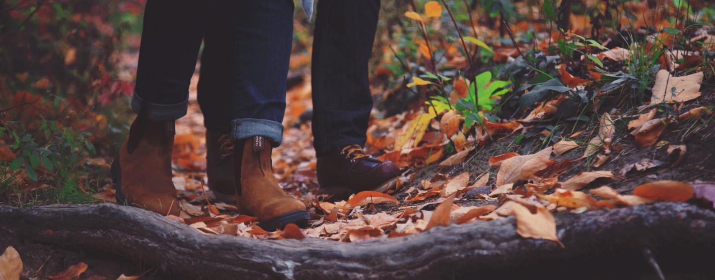 Feet and lower legs of two people standing on forest ground
