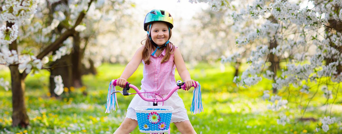 Happy girl on bike amongst cherry blossoms